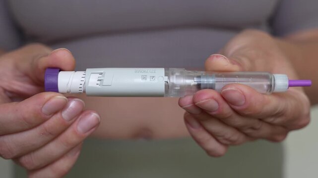 Woman setting dosage clicks on GLP-1 injection pen close-up