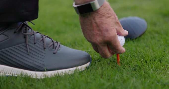 Hands, golf ball and exercise or tee, sports and competition on grass, challenge and tournament. Person, relax and closeup for game, practice and hobby or recreation, action and equipment for match