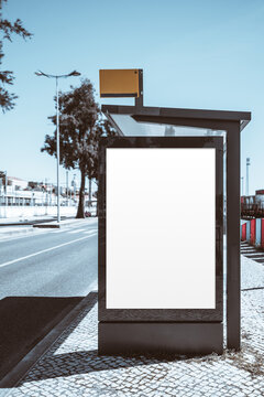 Blank illuminated poster template in modern bus stop shelter beside a quiet city street, ready for outdoor advertising, branding preview, signage design or urban campaign display