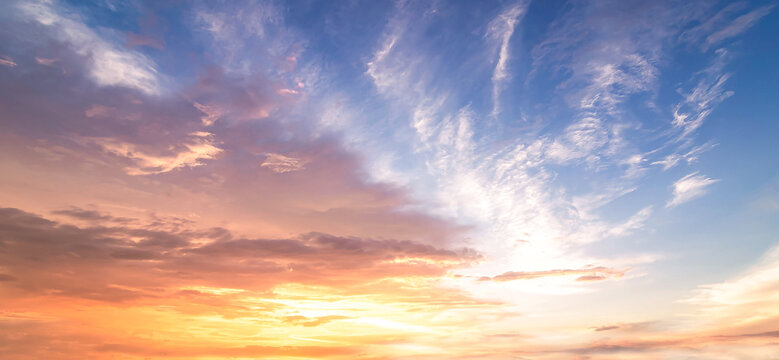 Beautiful vibrant twilight sky background with dramatic colorful orange and blue cirrus clouds at sunset for inspirational nature wallpaper panorama
