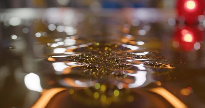 Close-up of water ripples and vibrations on a dark liquid surface
