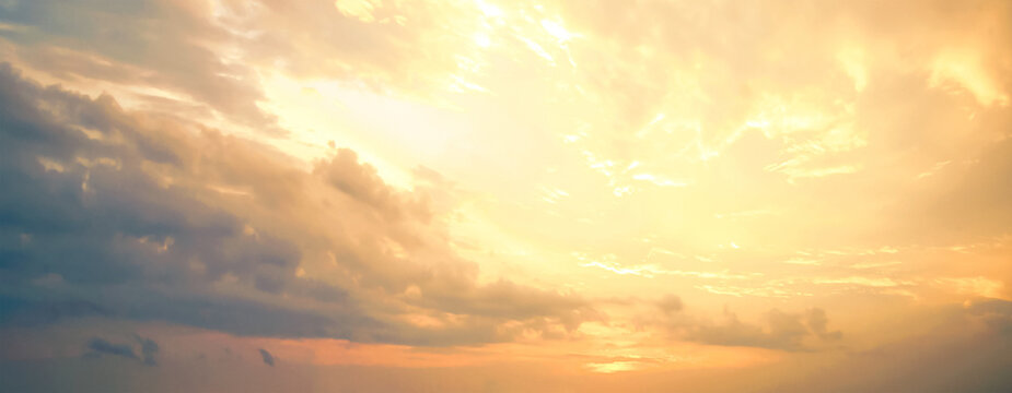 Beautiful dramatic golden twilight sky background with dynamic yellow orange clouds at sunset for inspirational nature wallpaper panorama