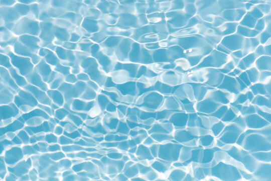 Blue water with ripples on the surface. Defocus blurred transparent blue colored clear calm water surface texture with splashes and bubbles. Water waves with shining pattern texture background.