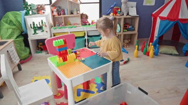 Girl building with colorful plastic blocks on a play table, hands arranging pieces while standing in a playroom building; concentration creativity.