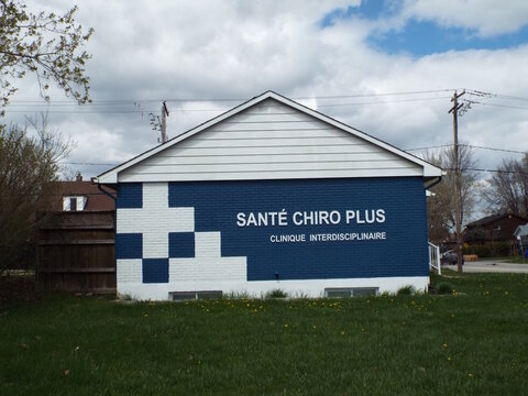 Gatineau, Quebec, Canada &ndash; May 7, 2026: Exterior view of the "Sant&eacute; Chiro Plus" building featuring a painted blue brick wall and grassy lawn on at 1 Rue Isabelle.