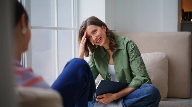 Carefree lady chatting friend holding book relaxing in modern apartment closeup.