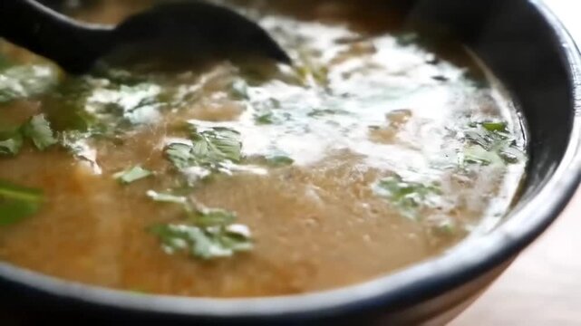 Close-up of a ladle scooping delicious hot soup from a bowl.