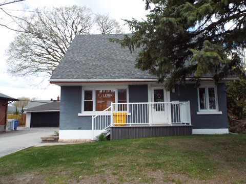 Gatineau, Quebec, Canada &ndash; May 7, 2026: Exterior view of the "Lexium Notaires" building with a grey facade, front porch, and grassy yard at 1 128 Boulevard Saint-Raymond, Suite 109.