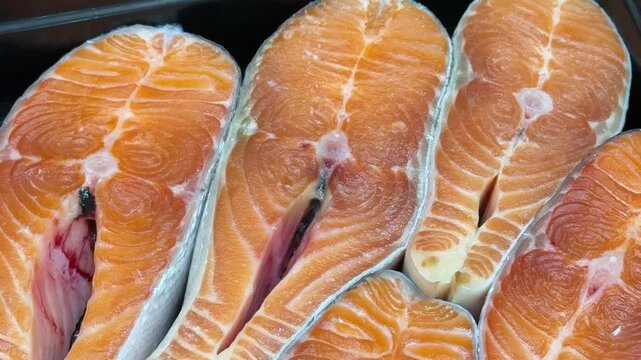 Steaks of chilled Atlantic salmon from frozen raw materials on a substrate for sale in a supermarket. Close-up