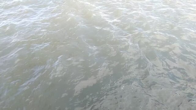 Top view of murky river water surface with gentle ripples and waves