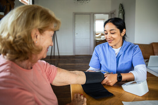 Nurse checking senior woman's blood pressure at home