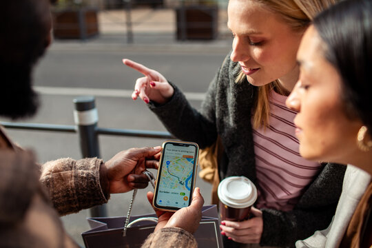 Friends using rideshare app on city street