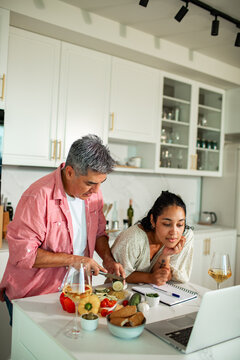 Couple cooking dinner while following online recipe in home kitchen