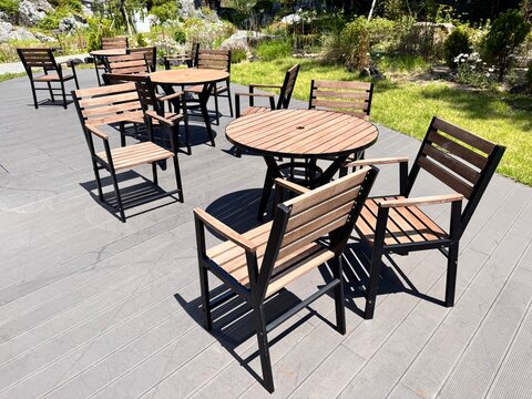 Empty wooden tables and chairs on an outdoor terrace in a garden park