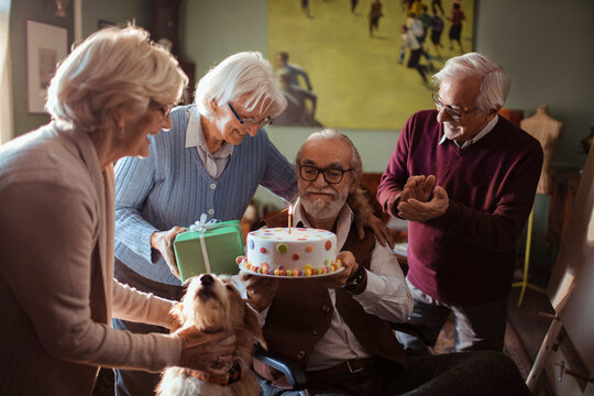 Senior friends celebrate birthday with cake at home