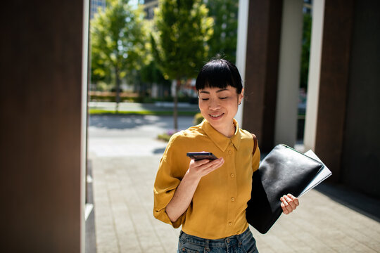 Young woman using voice command on smartphone outdoors in city
