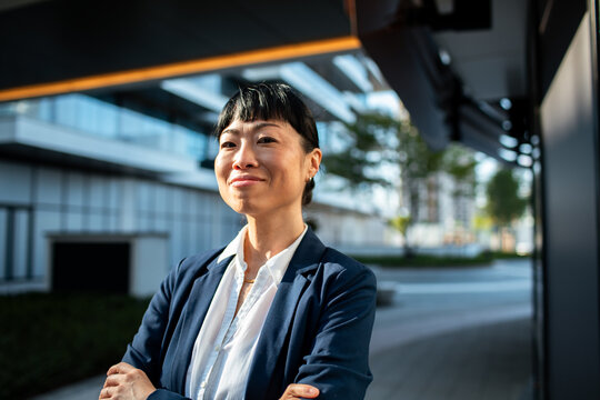Smiling businesswoman with arms crossed outside modern office