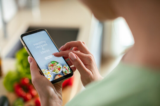 Woman browsing healthy recipe app in home kitchen
