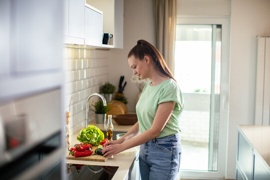 Young woman chopping vegetables in modern home kitchen