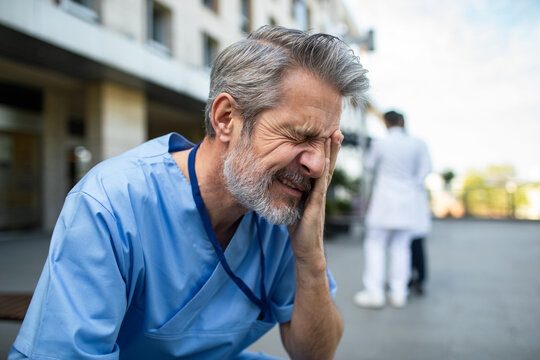Stressed healthcare worker in scrubs outside hospital