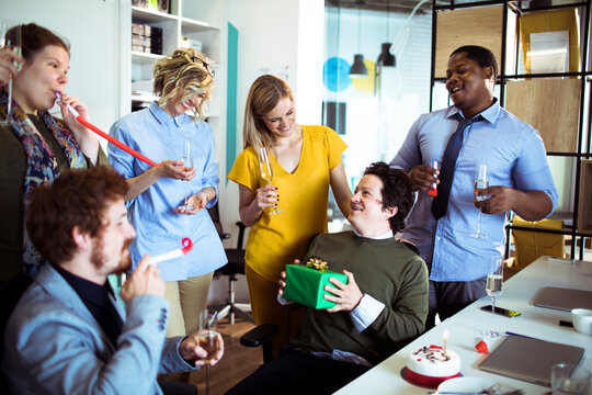 Diverse team celebrating coworker's birthday in modern office