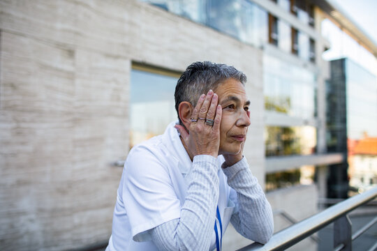 Worried healthcare worker resting outside hospital