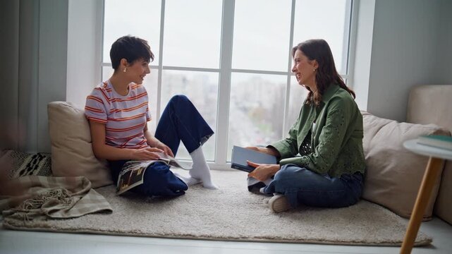 Cute besties laughing home living room joking enjoying leisure time together. 