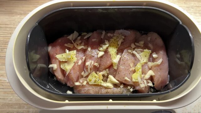 Close-up steamed chicken fillet with garlic in double boiler, fresh raw meat topped with butter slices and cracked pepper, home