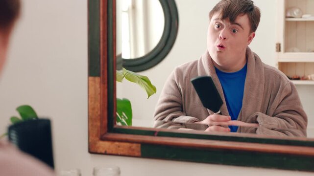Mirror, happy and teenager brushing hair in bathroom for grooming or self care in home. Goofy, reflection and male person with down syndrome in house for getting ready in morning with hairstyle.