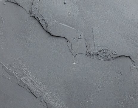 Close-up of a textured, grey surface with a crack running diagonally. The rough, layered texture creates depth