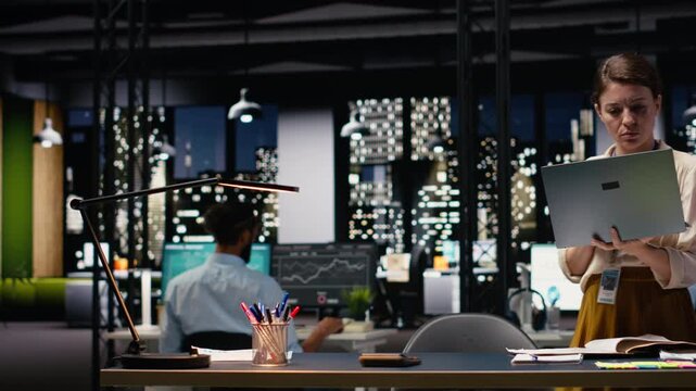 Woman employee looking over paperwork and data on laptop, preparing budget reports before deadline. Female consultant documenting company balance sheets and income statements at night.