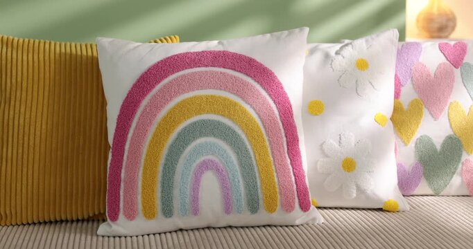 Colorful pillows on soft sofa indoors, closeup. Camera moving forward and right