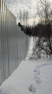 Snow cleared pedestrian path alongside highway, showing salted and grit strewn surface, high plow berm, tire tracks and compacted