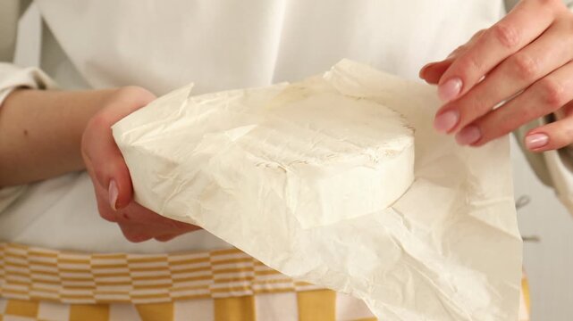 Woman showing delicious brie cheese, closeup view