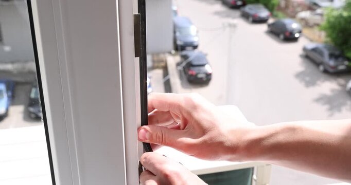 Handyman installing rubber gasket on window indoors, closeup
