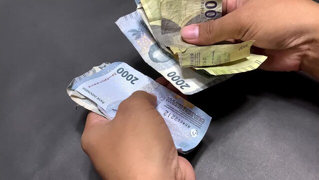 hands counting small denomination Indonesian rupiah banknotes.