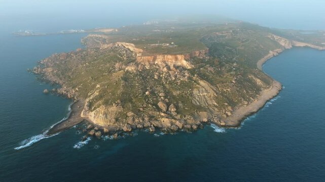 Aerial drone approach toward rugged limestone coastal cliffs on western Malta coastline with dramatic terrain reveal