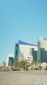 Vertical video Orbi City view, fast flow of people on the embankment. Timelapse view of the famous buildings of Batumi, Georgia, Adjara region
