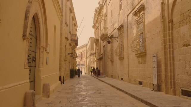 Cinematic walking shot through narrow limestone streets of Mdina old town Malta with historic architecture