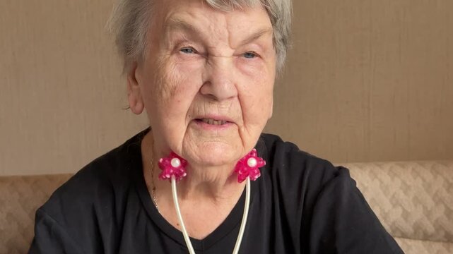 Elderly woman neck massage red roller tightening double chin close-up, pink twin rollers gliding along jaw and neck, seated at home