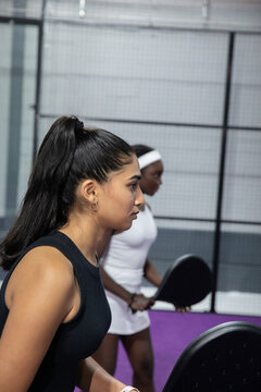 Diverse women athletes in tennis dress and tank training on purple court with paddles, copy space