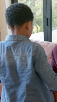 Vertical video: Reacting to maroon-sweater adult, denim shirt child reaching by glass door, couch