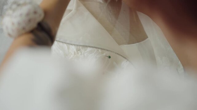 Fashion designer arranging floral lace appliques on luxury wedding dress in bridal atelier