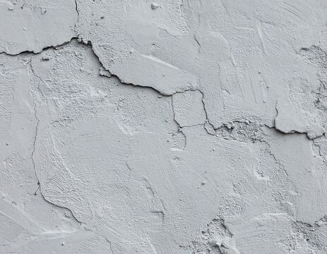 Close-up of a textured white wall with cracks and imperfections, revealing a weathered surface