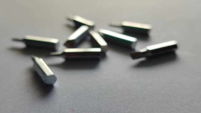 Scattered screwdriver bits on surface, showing mechanical tools and workshop equipment detail in close-up view.