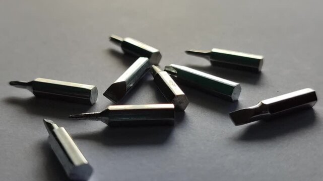 Scattered screwdriver bits on surface, showing mechanical tools and workshop equipment detail in close-up view.