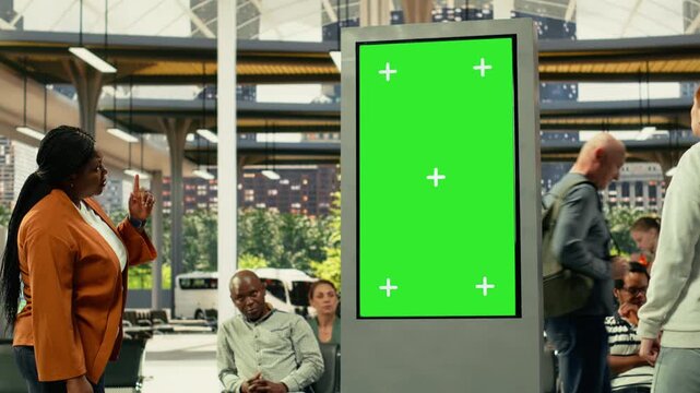 Green screen TV near dynamic city transportation scene with diverse people on the move in crowded bus terminal. Commuters of different ages create realistic everyday travel routine.