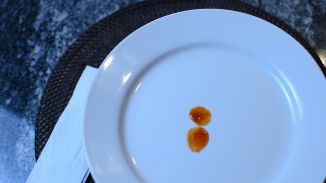 Ketchup dripping onto a medium sized white saucer. 