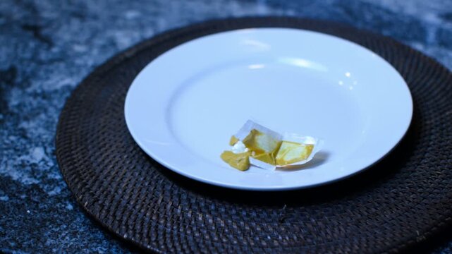 To go mustard condiment packet on a white saucer. 