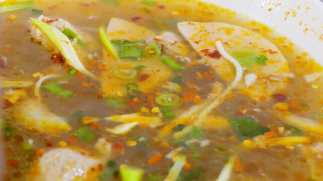 Using chopsticks to eat spicy Vietnamese Bun Bo Hue beef noodle soup